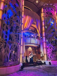 a man playing a guitar in the lobby of a cruise ship