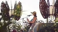 a woman is playing an acoustic guitar on a stage