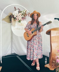 a woman playing an acoustic guitar in front of a tent