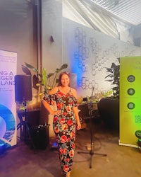 a woman in a floral dress standing in front of a banner