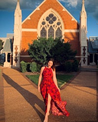 a woman in a red dress standing in front of a church