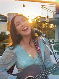 a woman singing into a microphone while playing an acoustic guitar