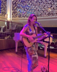 a woman playing an acoustic guitar in front of a microphone