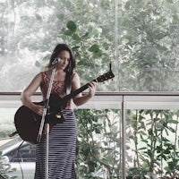 a woman playing an acoustic guitar in front of a window