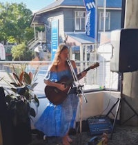 a woman playing an acoustic guitar in front of a window